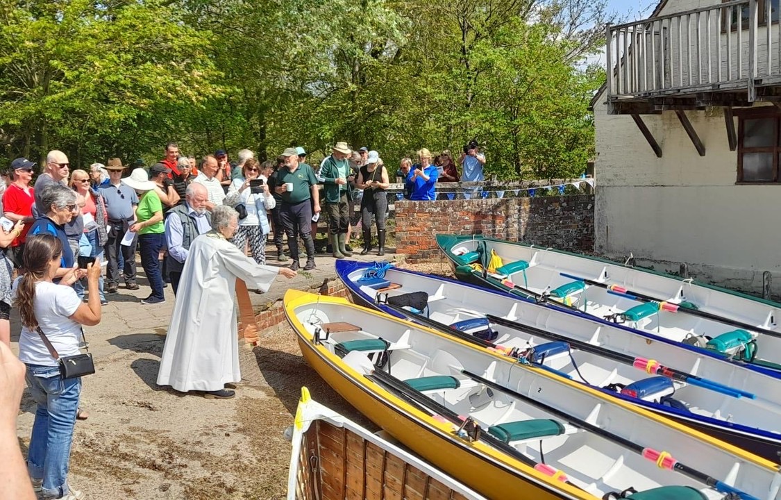 People gathered beside fixed-seat boats during a boat blessing.